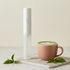 Espumador de leche Hindie junto a un matcha latte con latte art en una taza rosa tierra